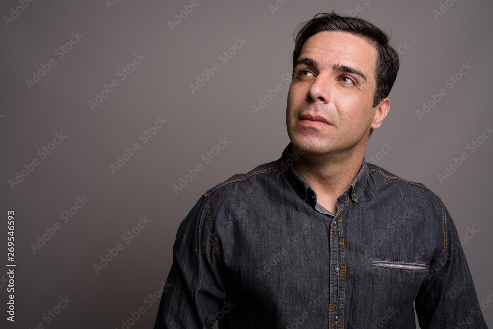Portrait of handsome Persian man against gray background
