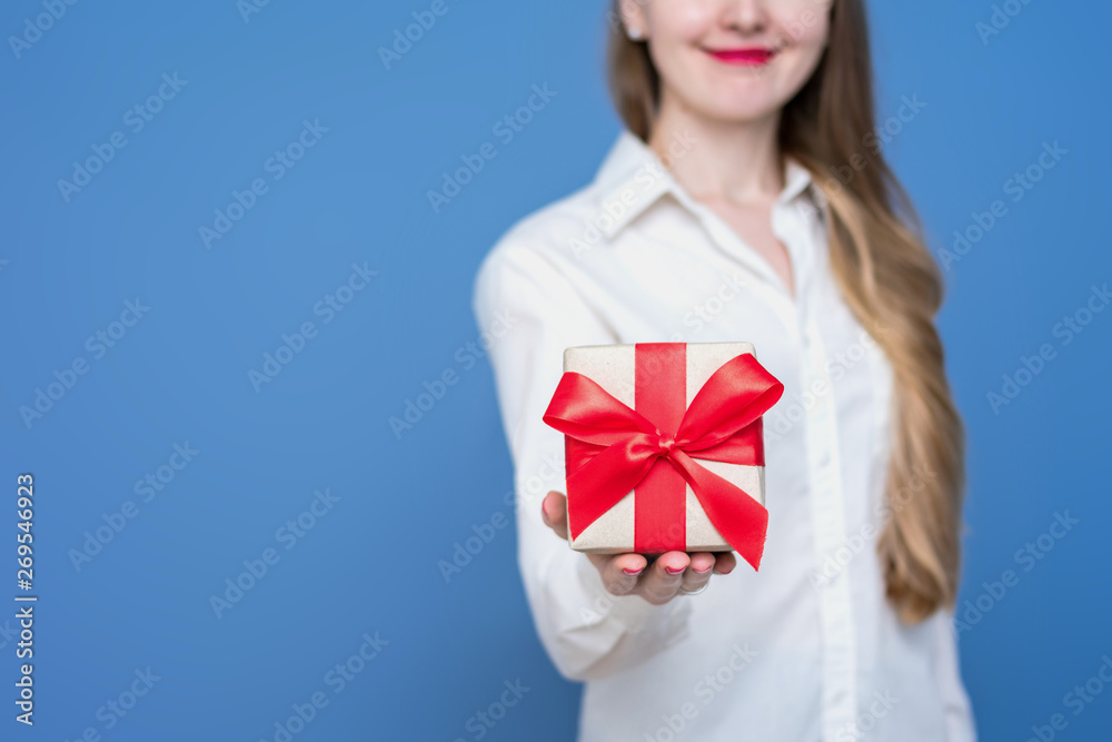 Woman in white shirt holding a box with a gift with a red ribbon, front view, close up, copy space Woman in white shirt holding a box with a gift with a red ribbon, front view, close up, copy space