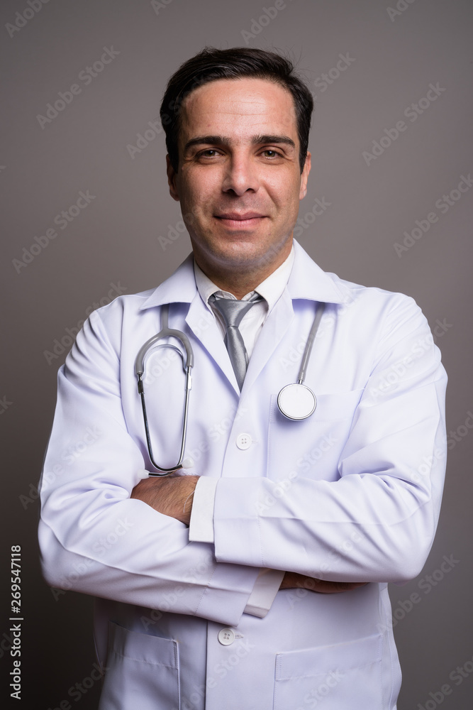 Handsome Persian man doctor against gray background Handsome Persian man doctor against gray background