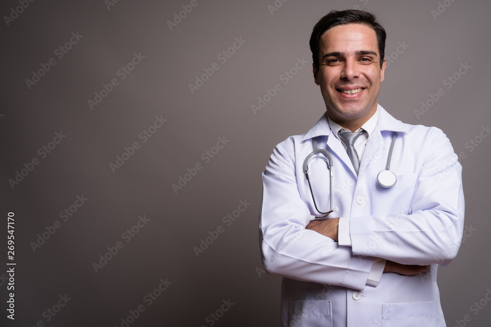 Handsome Persian man doctor against gray background Handsome Persian man doctor against gray background