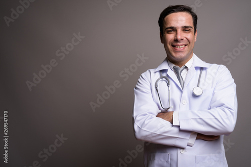 Handsome Persian man doctor against gray background