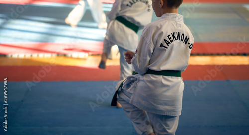 Martial arts. A young man in a white kimano with a green belt. Demonstrates Taekwondo Tuli.