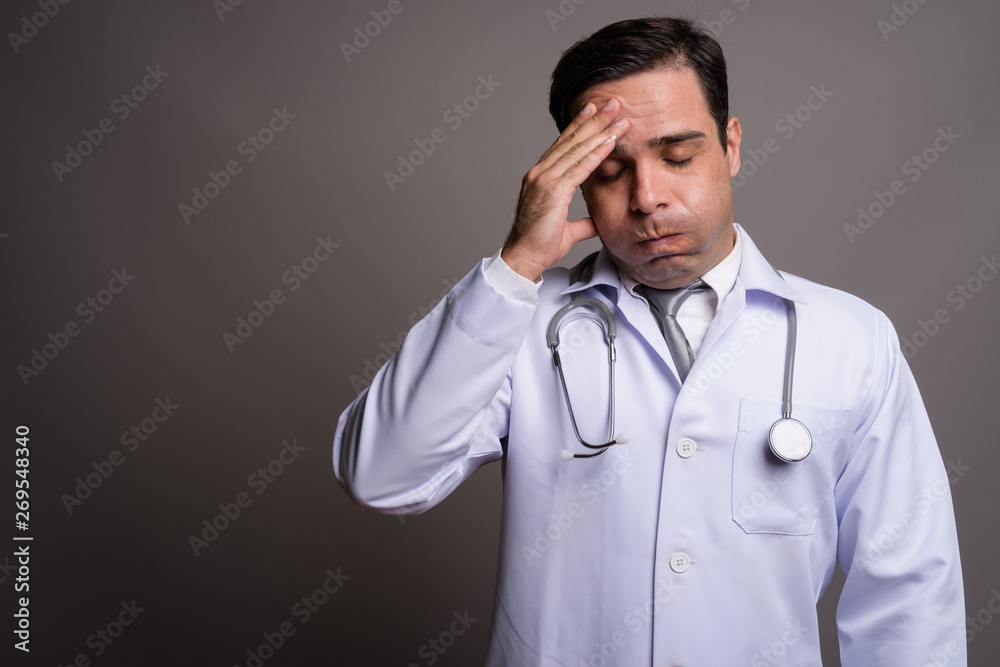 Handsome Persian man doctor against gray background Handsome Persian man doctor against gray background