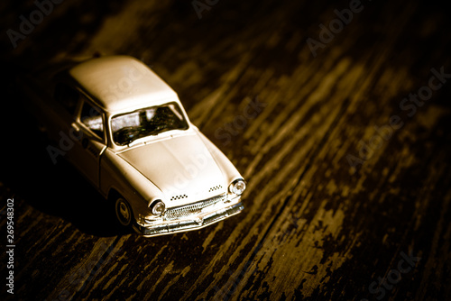 Collectible toy model of an old car with a taxi symbol on a wooden background. Selective focus. Copy space. © Андрей Киселев