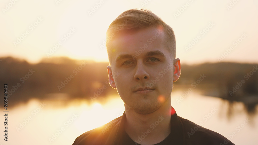 Portrait of young handsome man enjoying sunlight during sunset