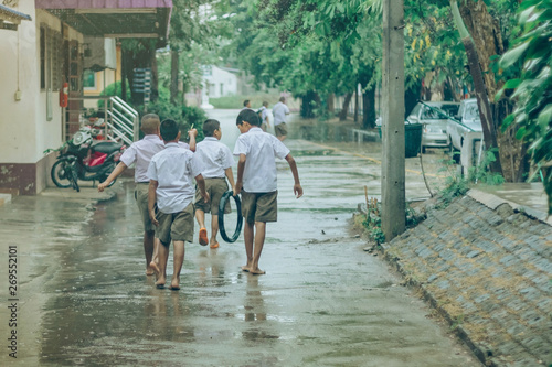Boy students leave the classroom to walk on the street after heavy rain in the school.