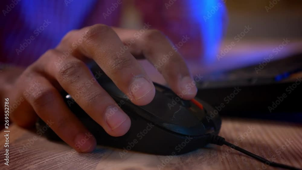 Closeup shoot of indian male hands using the mouse and typing on the computer indoors in a cozy apartment with neon light Closeup shoot of indian male hands using the mouse and typing on the computer indoors in a cozy apartment with neon light