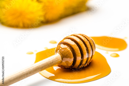 Flowery golden honey drop and stick in honey on white background