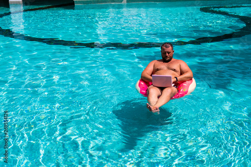 Male freelancer with a laptop on rubber ring in the water