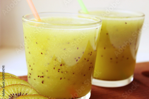 Summer refreshing drink. Healthy food, vegetarianism. Kiwi smoothie in a glass next to fresh kiwi slices on a wooden table. fruit drink.copy space