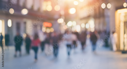 Group of unrecognizable anonymous people in bokeh walking on a street in the evening. Defocused image photo