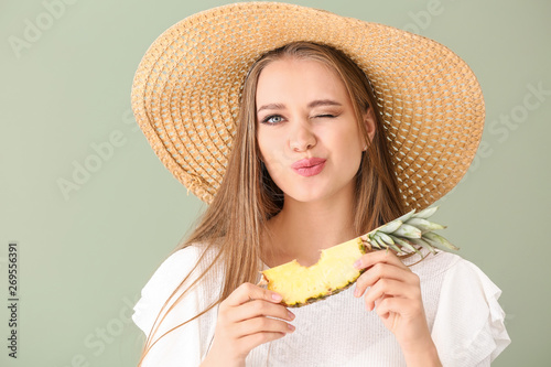 Fotografía Beautiful young woman eating pineapple on color background