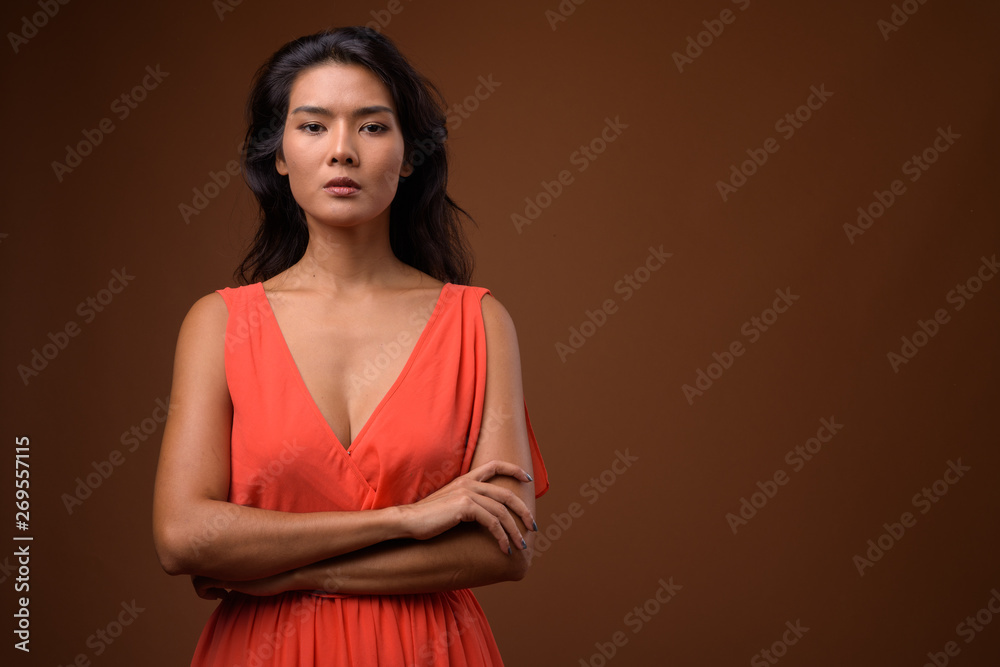 Obraz premium Studio shot of beautiful Asian woman against brown background