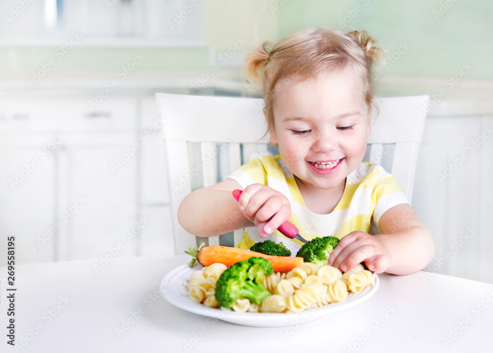 Child girl sitting at table with a plate of food,kid eating vegetables. - obrazy, fototapety, plakaty 