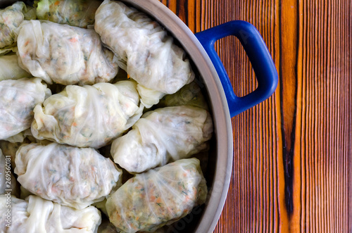 Cabbage Rolls or Dolma. Stuffed cabbage leaves with minced meat, rice, vegetables and herbs in casserole. Isolated on rustic wooden table, copy space for your text. Top view. Sarma, golubtsy, golabki. photo