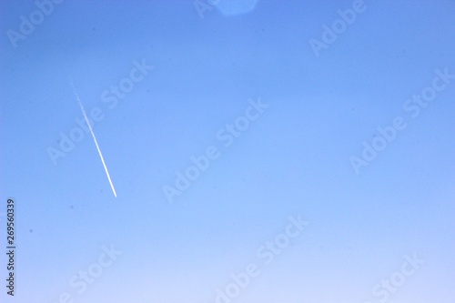 blue sky and white trace of a plane flying high, background
