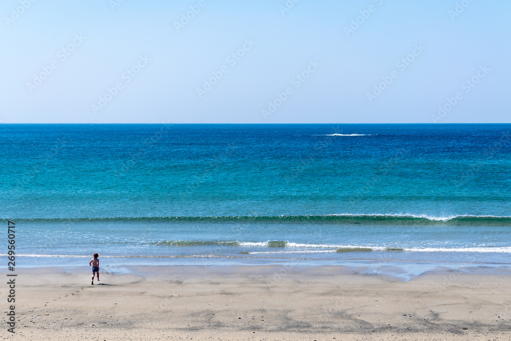 Boy running to the blue sea