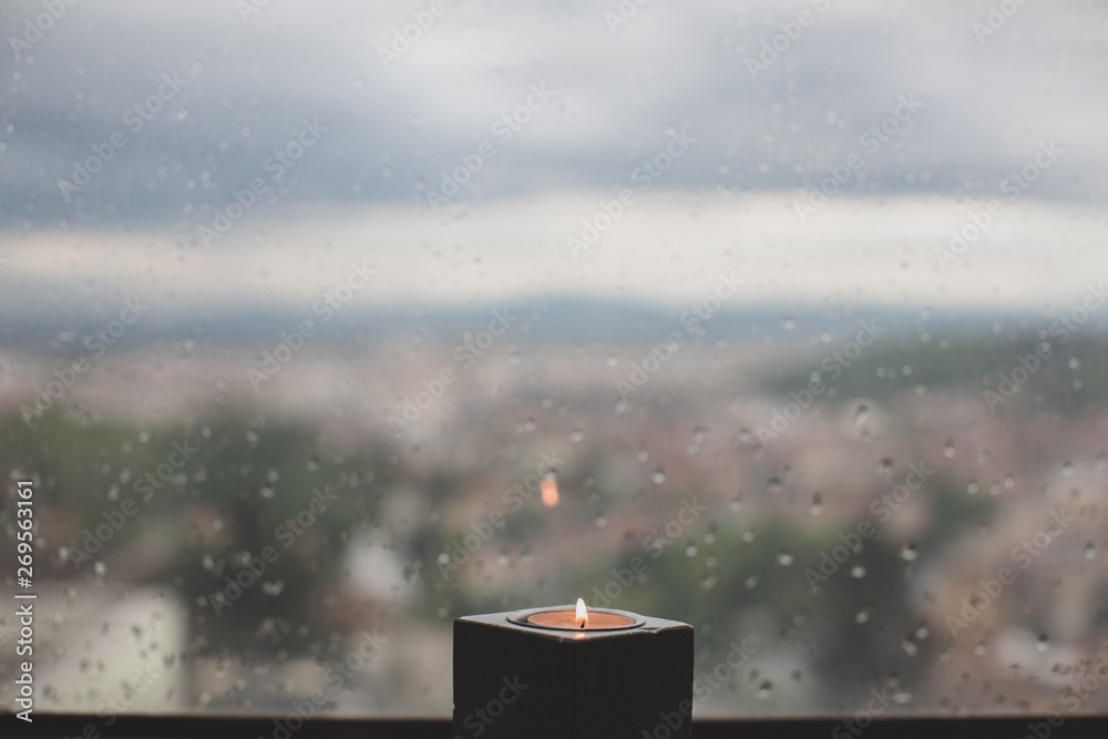 view of a candle in a window with rain outside