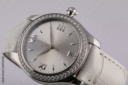 Female silver watch with a light grey dial, silver clockwise, chronograph, with a white leather strap isolated on white background