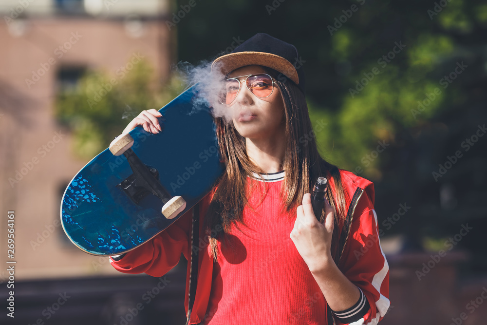 Vaping girl. Young woman with skateboard vape e cig. Pretty young