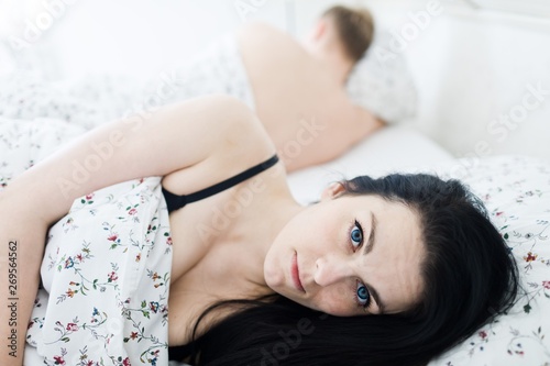 Desperate young woman with open eyes in bed.