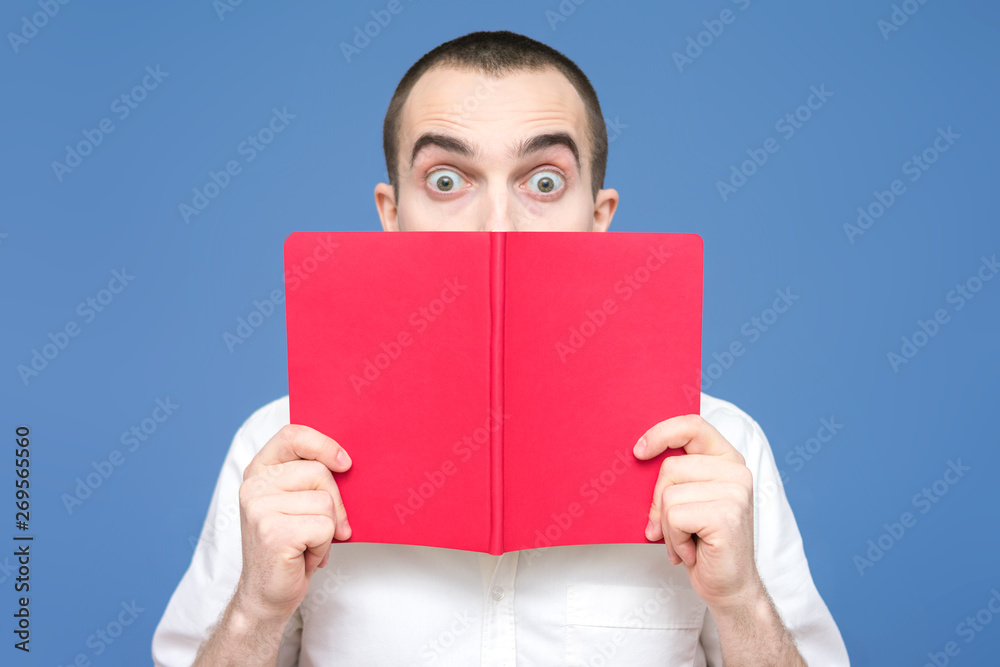 Male reads the book, visible only eyebrows, stares in surprise at the camera, facial expressions, close up, background, copy space, for advertising Male reads the book, visible only eyebrows, stares in surprise at the camera, facial expressions, close up, background, copy space, for advertising
