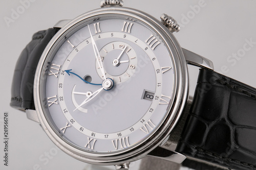 Silver wristwatch with white dial, silver clockwise, stopwatch and chronograph on black leather strap on white background