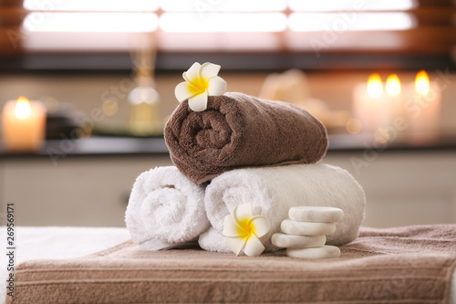 Composition with towels, flowers and stones on massage table in spa salon