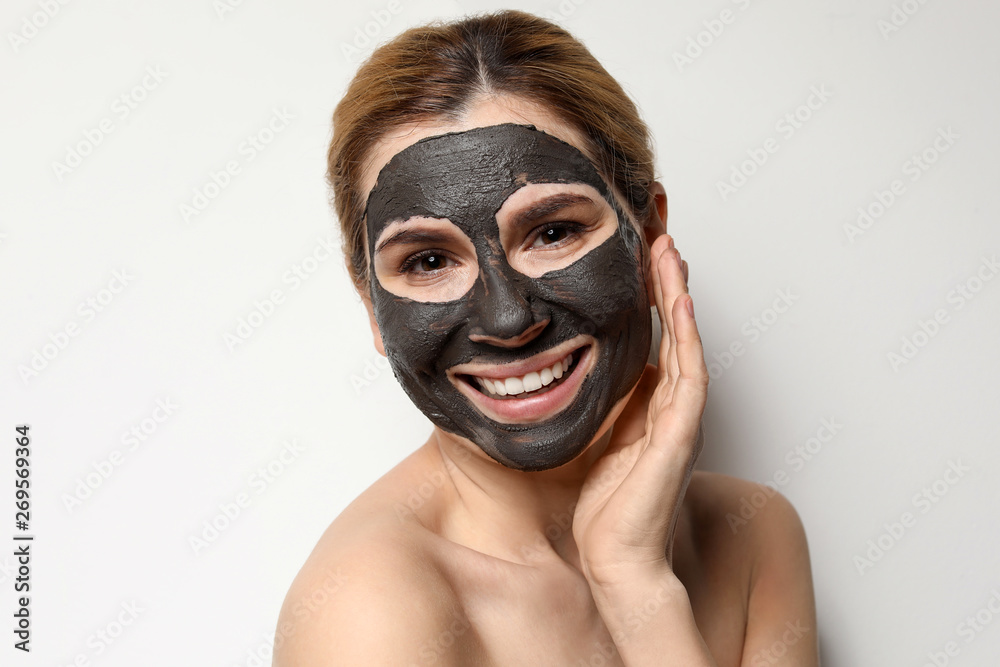 Beautiful woman with black mask on face against light background