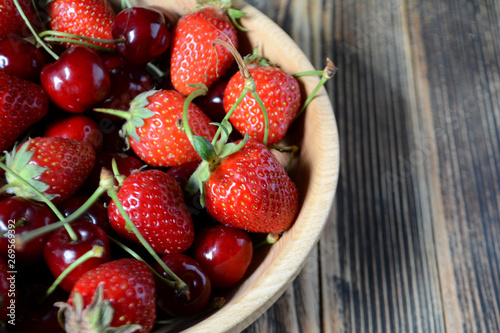 Strawberries and cherries in a brown wooden bowl. Fresh organic summer berries