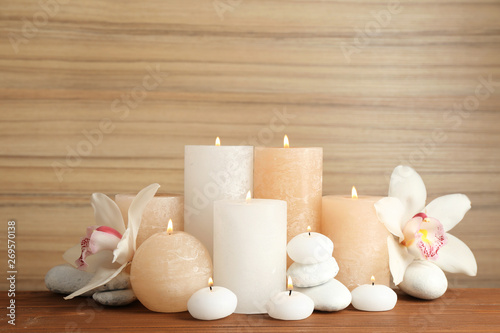 Beautiful composition with lit candles and flowers on table