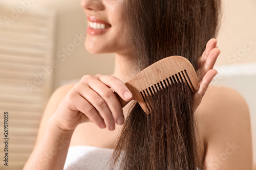 Beautiful young woman with hair comb in bathroom, closeup