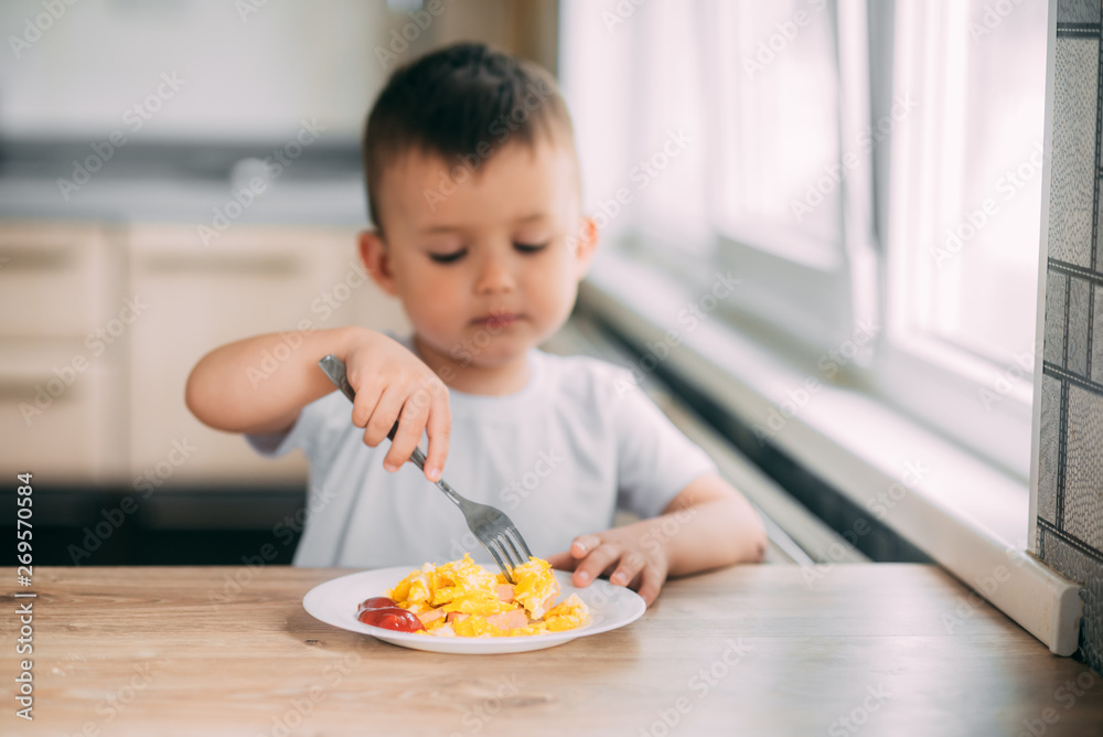 child day in the kitchen eating an omelet with sausage and ketchup