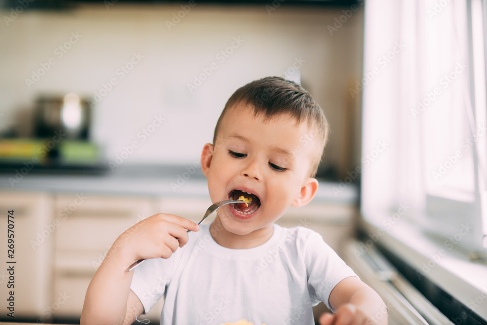 child day in the kitchen eating an omelet with sausage and ketchup child day in the kitchen eating an omelet with sausage and ketchup