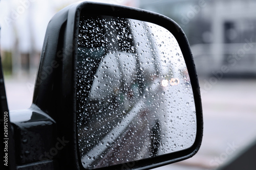 Closeup of car side rear view mirror with rain drops