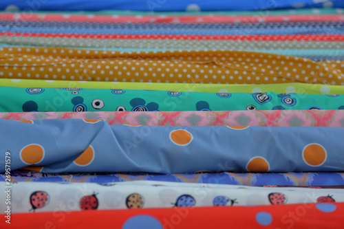 Bright multi-colored fabrics in rolls lie in a row on the counter of the oriental market photo