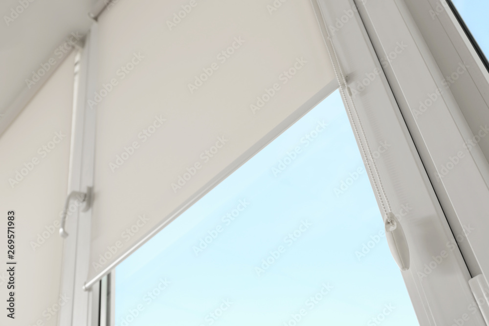 Window with modern roll blinds in room, closeup