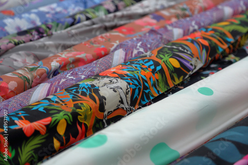 Bright multi-colored fabrics in rolls lie in a row on the counter of the oriental market photo