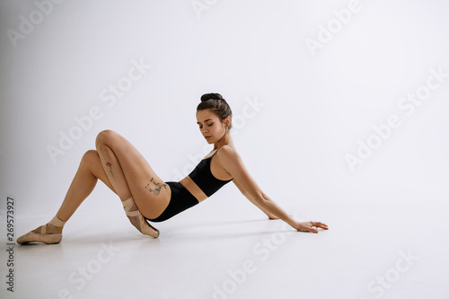 Fashion ballet. Young female ballet dancer in black bodysuit against white studio background. Caucasian ballerina like a fashion model. Style, contemporary choreography concept. Creative art photo. © master1305