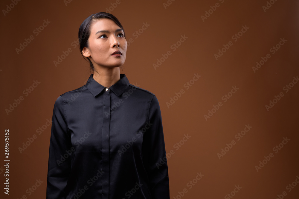 Obraz premium Studio shot of beautiful Asian businesswoman against brown backg