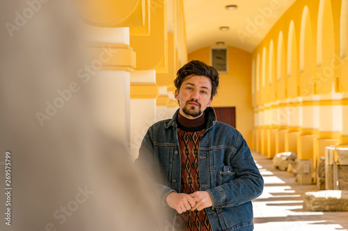 Portrait of a stylish handsome young man with a jaket outdoors.  A serious man wearing a denim jacket looking confident at the camera photo