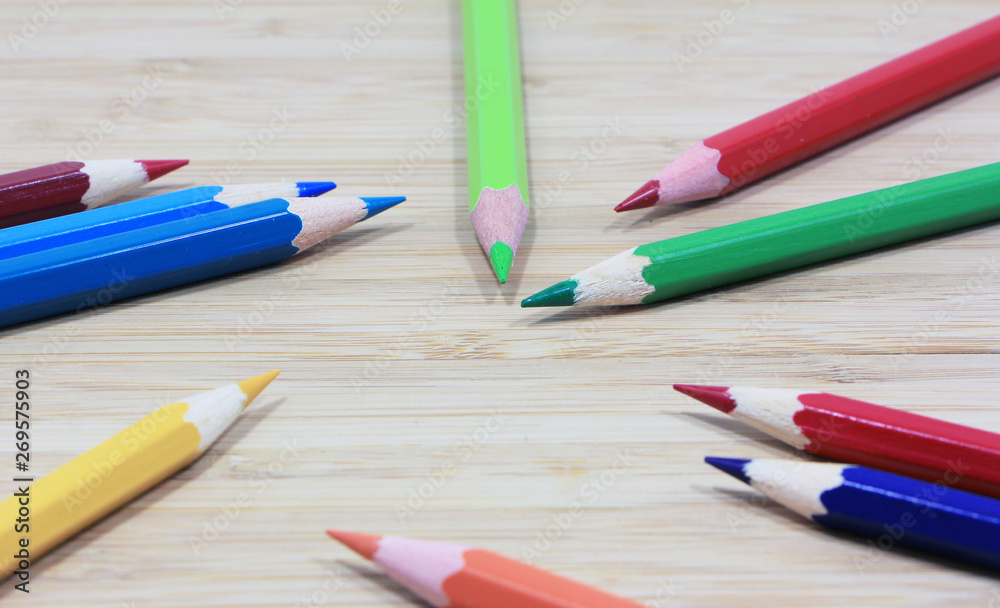 Background of colored pencils on a wooden surface.