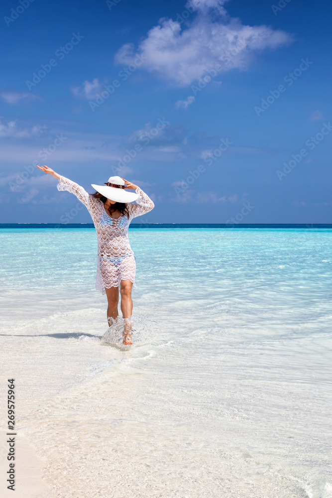 Attraktive Frau mit Sonnenhut läuft an einem Strand und genießt ihren tropischen Urlaub Attraktive Frau mit Sonnenhut läuft an einem Strand und genießt ihren tropischen Urlaub