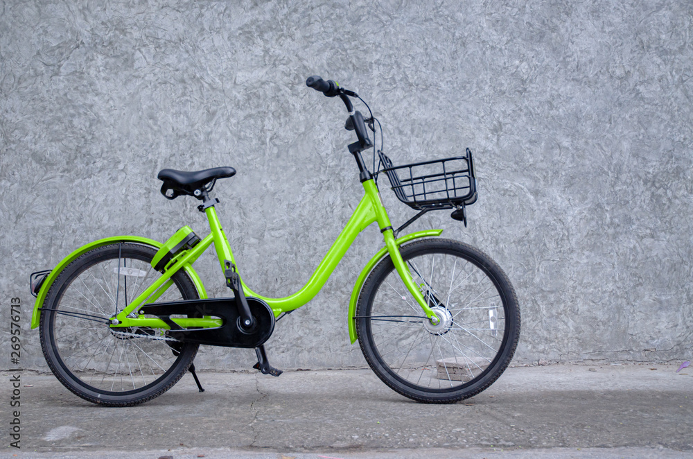 Green bicycle, black wheels parked on the wall.Vehicles with 2 wheels, driving with manpower.