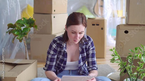 portrait tired young woman among the boxes to move,reads the Eviction Order Document money problem