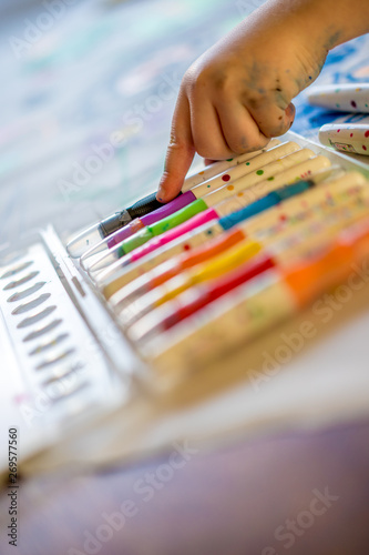 Childs hand pointing at colourful pens