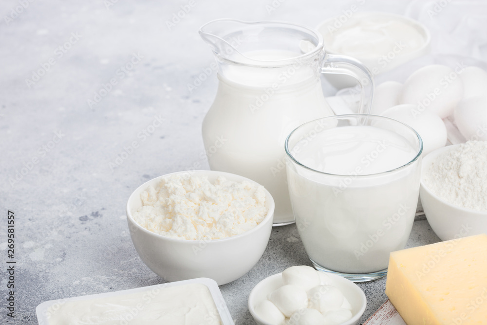 Fresh dairy products on white table background. Jar and glass of milk, bowl of sour cream, cottage cheese and baking flour and mozzarella. Eggs and cheese. Space for text Fresh dairy products on white table background. Jar and glass of milk, bowl of sour cream, cottage cheese and baking flour and mozzarella. Eggs and cheese. Space for text