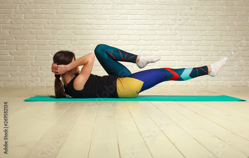 Young slim athletic woman doing fitness stretching exercises and pushups workout in studio healthy lifestyle