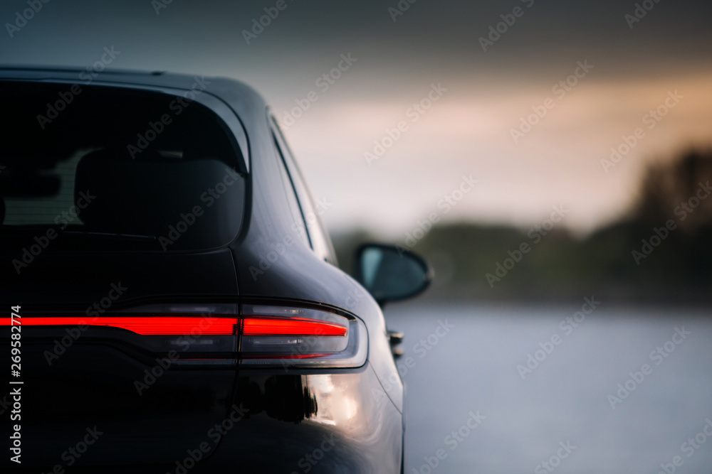 Modern suv car rear taillamp at evening near lake. LED tail lights is switched on during evening. Expensive and luxury crossover rear part with free space 