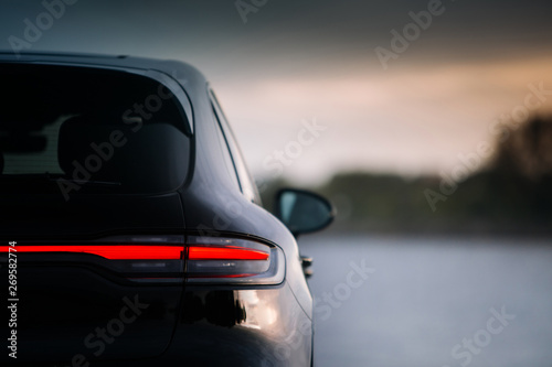 Modern suv car rear taillamp at evening near lake. LED tail lights is switched on during evening. Expensive and luxury crossover rear part with free space  photo